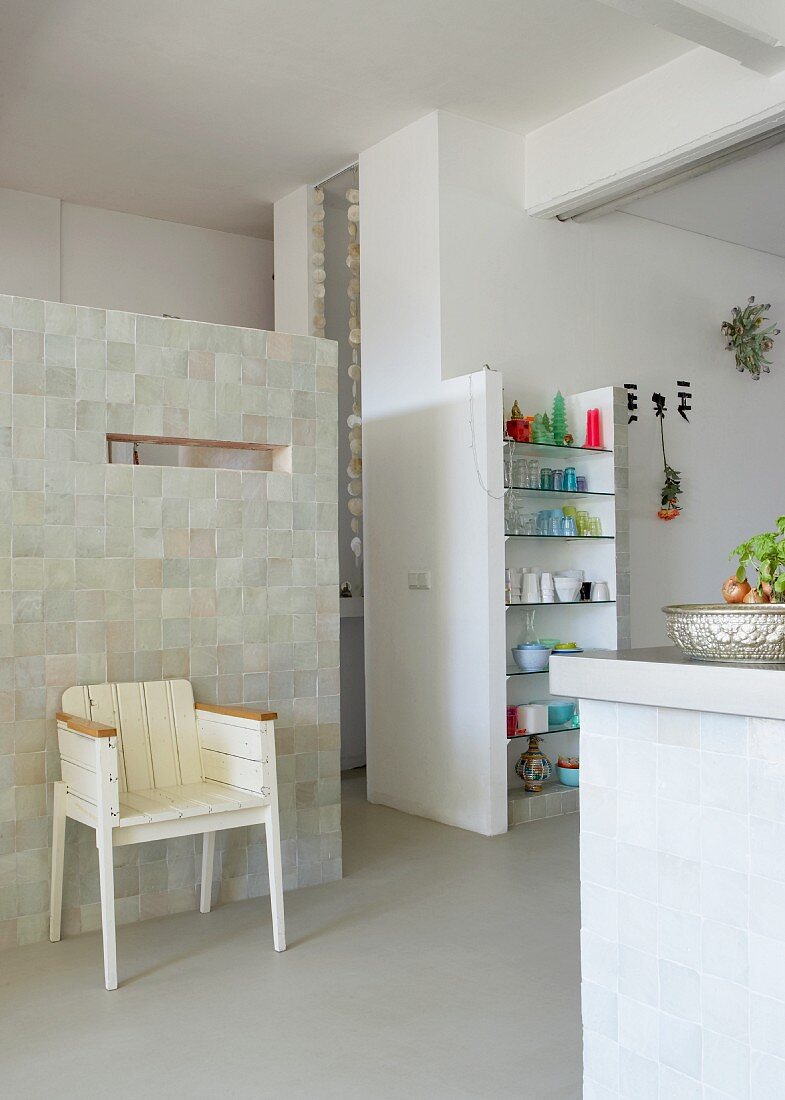 Loftähnlicher Wohnraum - Vintage Stuhl aus weiss lackiertem Holz an Wand eines Raumeinbaus und gemauertes Regal in offener Küche
