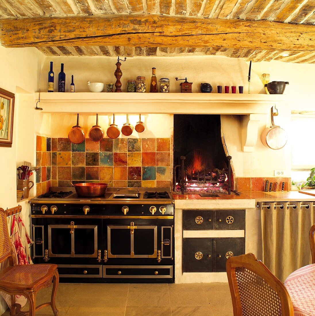 Mediterrane Küche mit Ziegeldecke und Baumstammbalken über stilvollem Retroherd und offener Feuerstelle