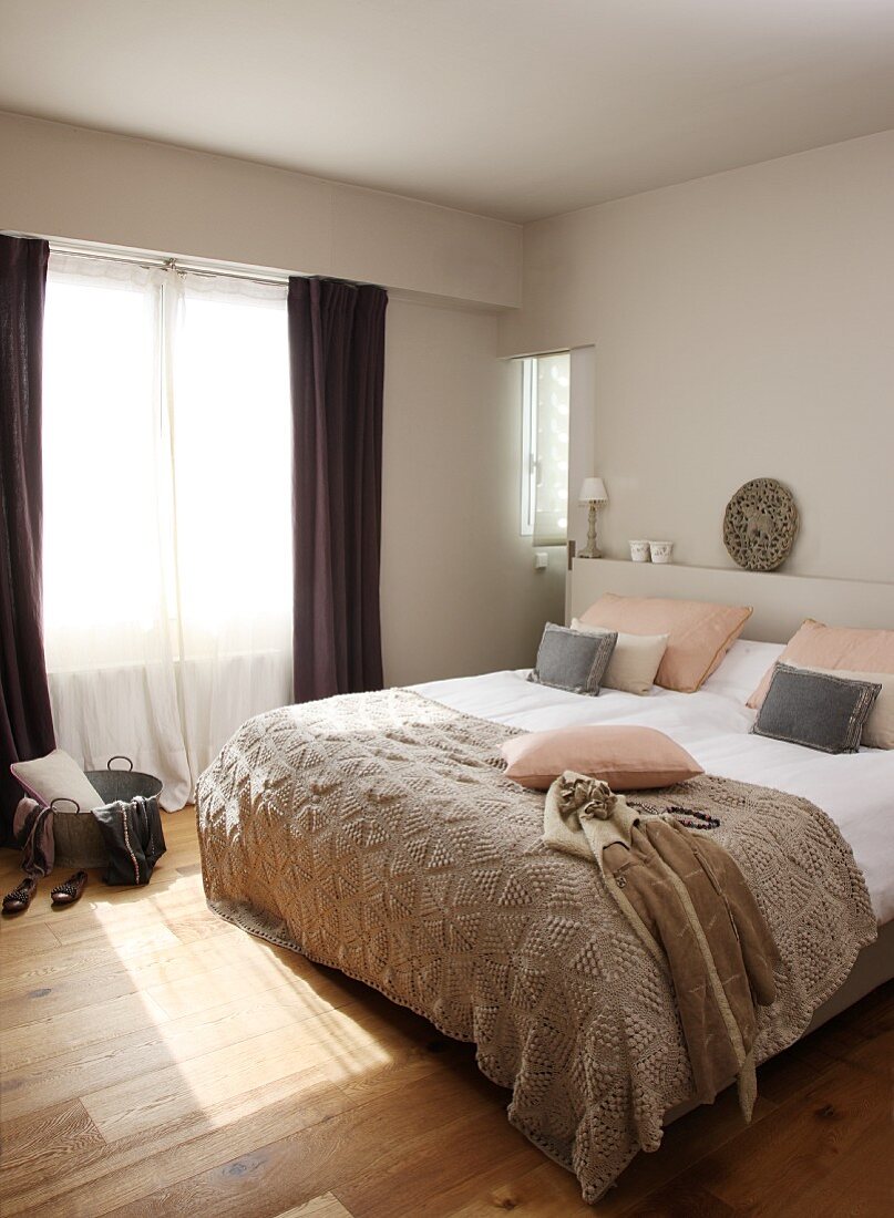 Modernes Doppelbett mit hellbrauner Tagesdecke in schlichtem Schlafzimmer