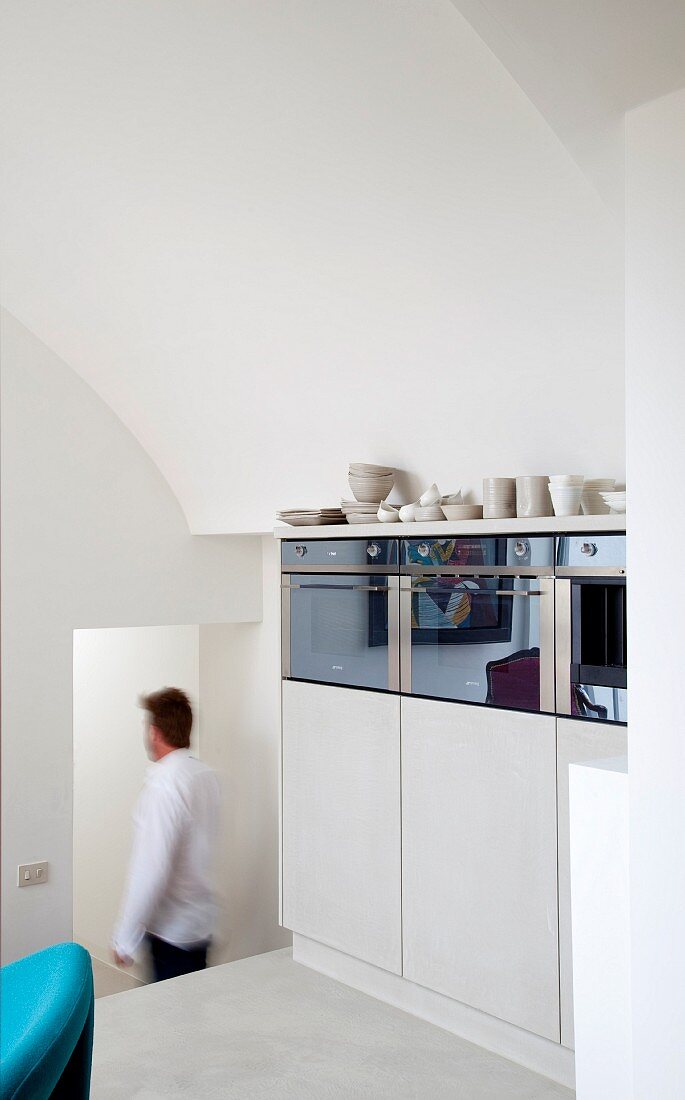 In verschachtelten Treppenabsatz optimal integrierter Geschirrschrank mit reflektierenden Glaselementen
