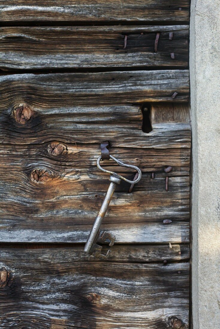 Alter Kapellenschlüssel an Haken einer Holztür hängend
