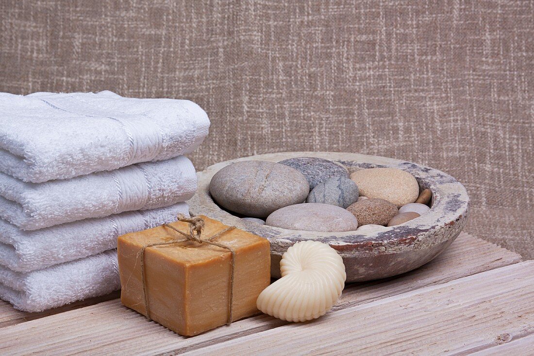 Wellness - Seifen und Handtücher neben Schale mit Steinen aufgefüllt