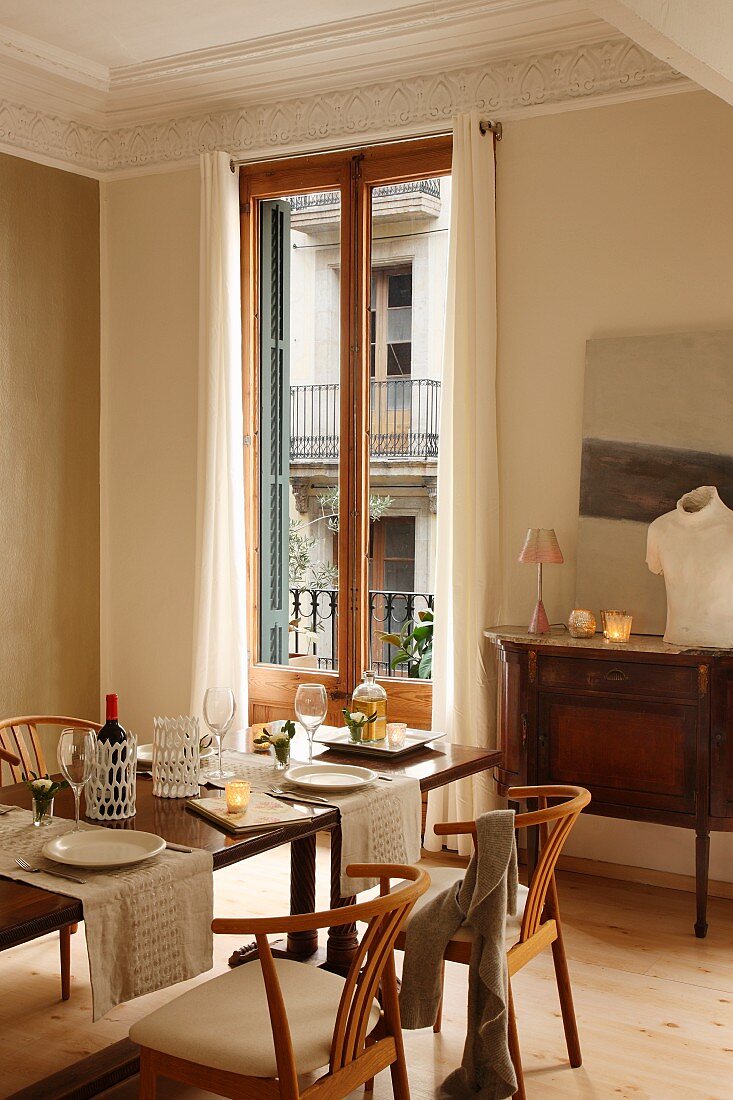 Klassikerstühle an gedecktem Tisch vor französischem Fenster in herrschaftlichem Esszimmer