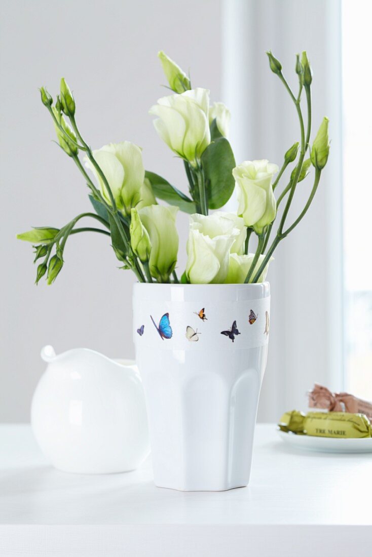 Masking Tape mit Schmetterlingsmotiv auf einer Vase mit weißem Lisianthus (Eustoma grandiflorum)