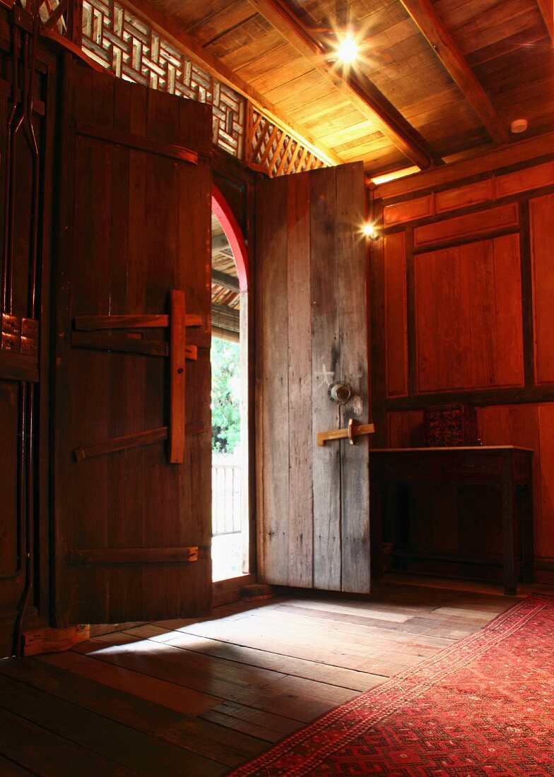 Traditional foyer with half-open front door in Oriental wooden house