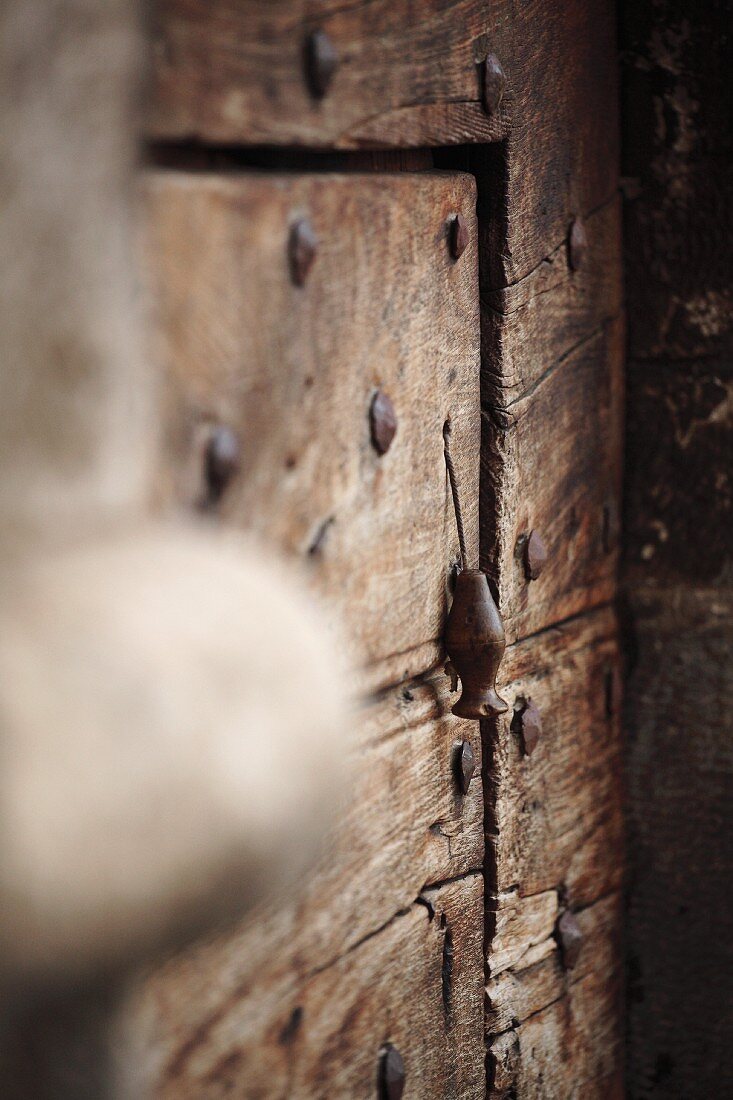 Provisorischer Türklopfer an alter Holztür mit Metall Nieten
