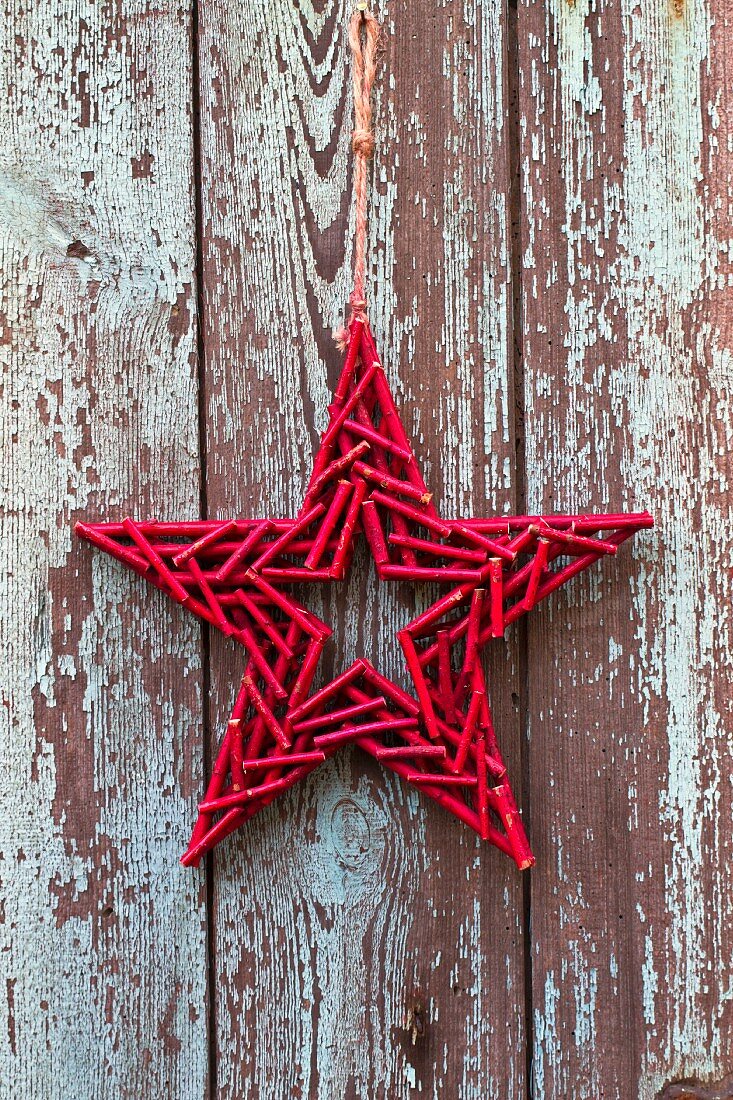 Stern aus roten Holzstäbchen an verwitterter Holzwand
