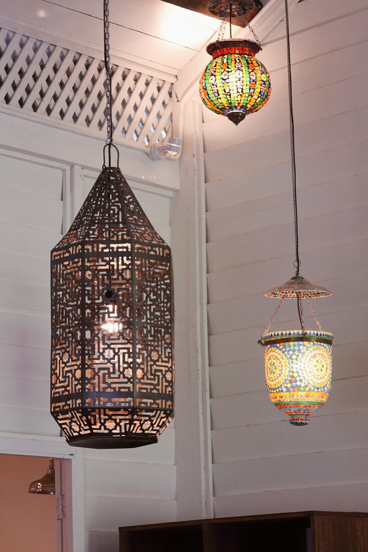 Various pendant lanterns, some with colourful lampshades, in corner of room