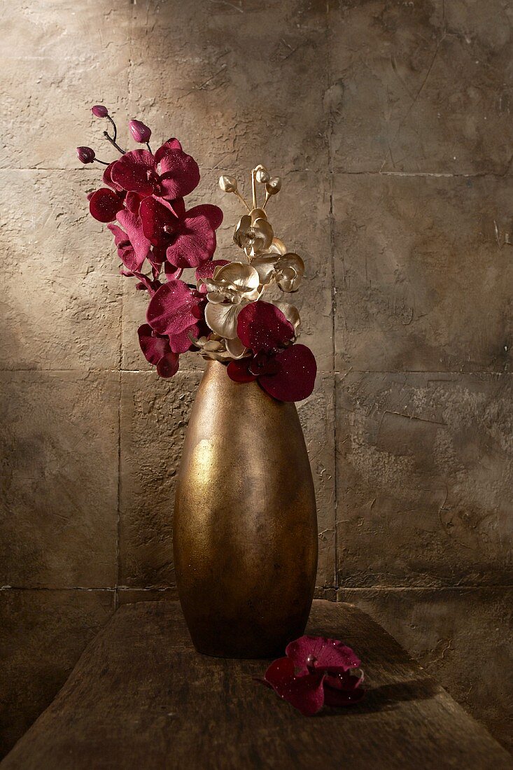Goldbraune Vase mit lila und goldfarbenen Orchideen