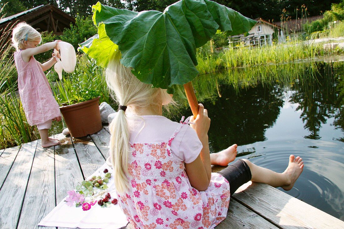 Two blonde girls next to garden pond