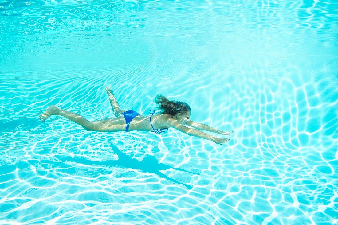 Frau im Bikini taucht im Swimmingpool