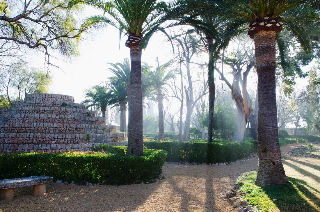 Tiered sculpture and palm trees in Mediterranean garden