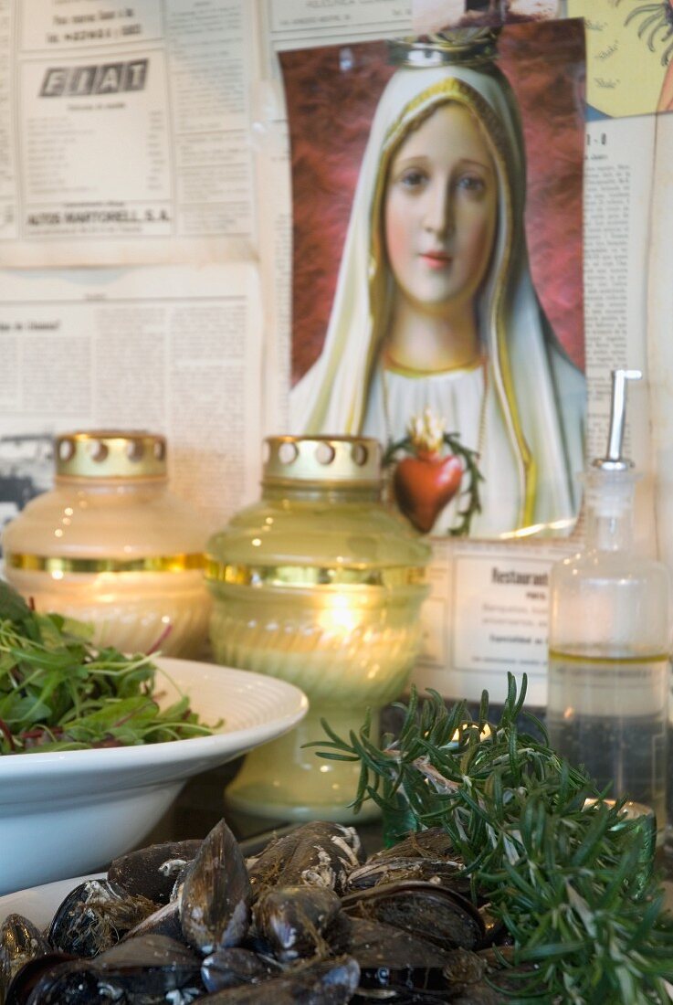 Mediterrane Gerichte und Windlichter vor Madonnabild an Wand