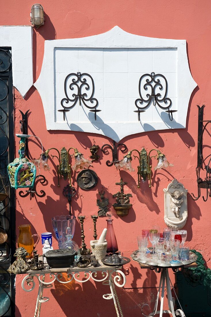 Flea market stall with antique sconces against brightly coloured, Mediterranean-style facade