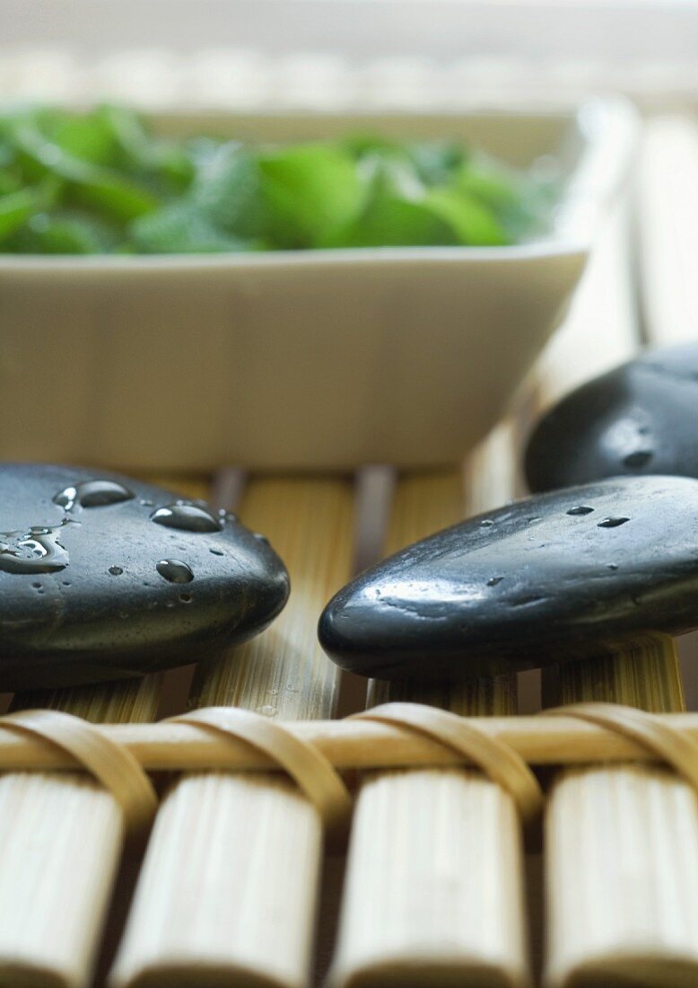 Schwarze Steine und Schale auf Bambusuntersetzer