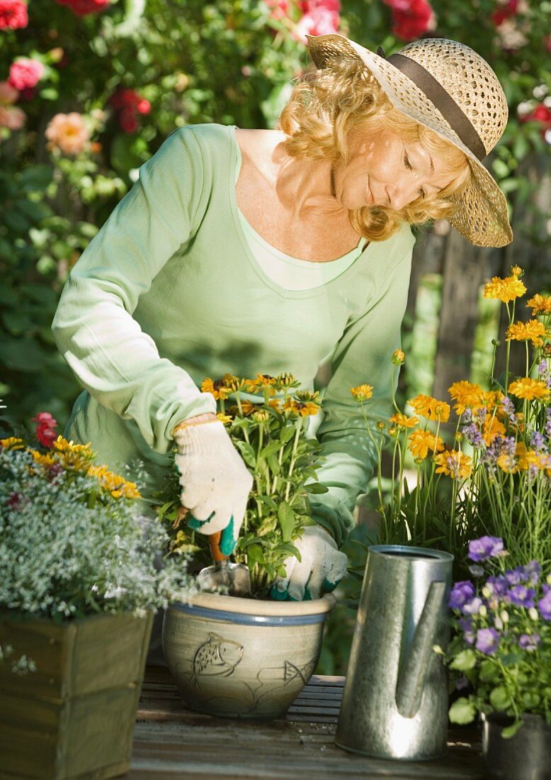 Frau setzt Blumen im Topf ein