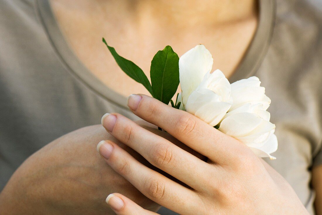 weiße Blumen in der Hand haltend