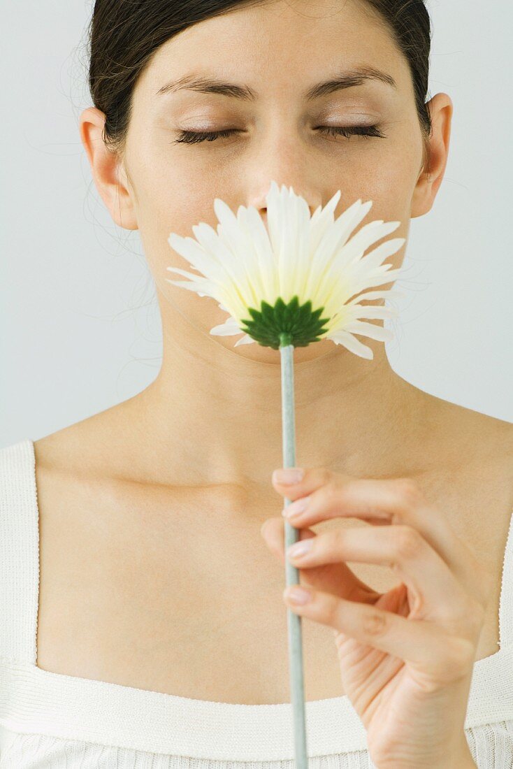 Frau hält Plastikblume vor ihr Gesicht