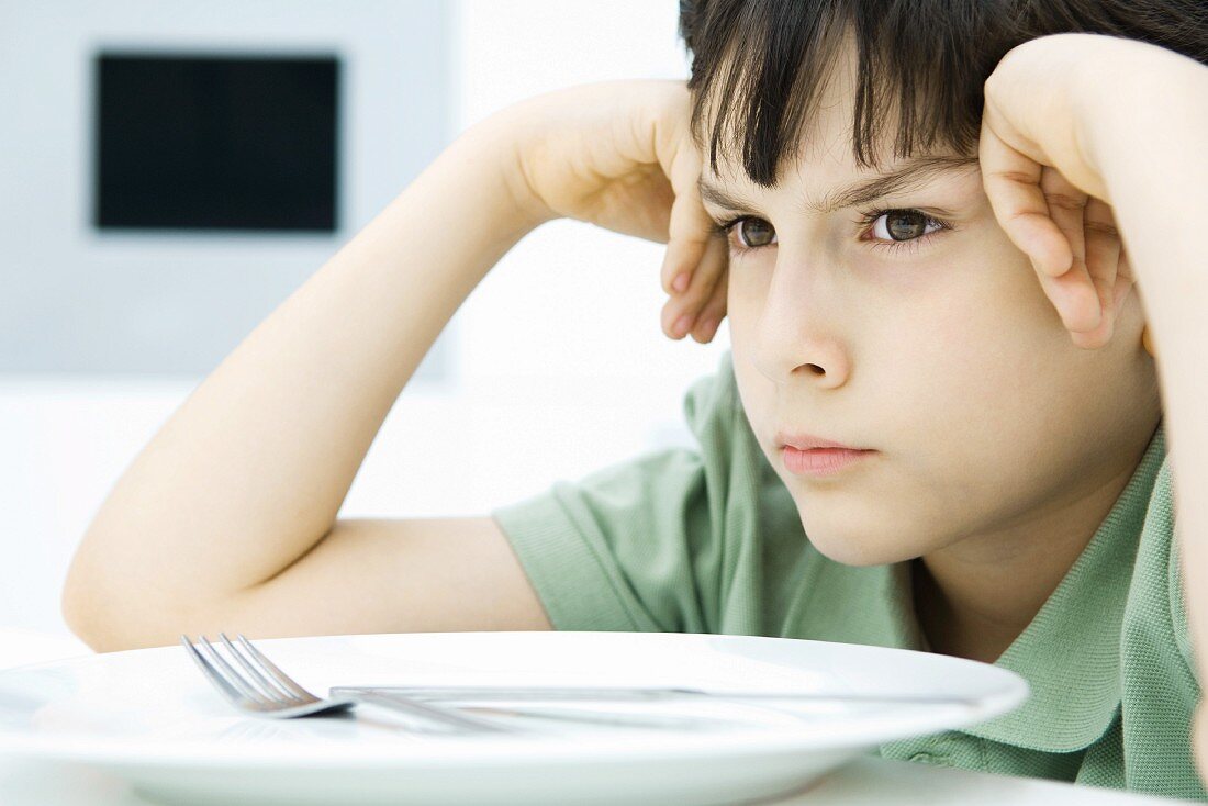 Boy sulking at dinner table, close-up