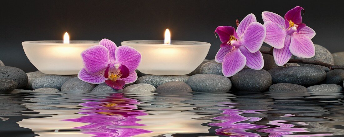 Entspannung im Spa - Teelichter und Orchideenblüten im Wasser gespiegelt