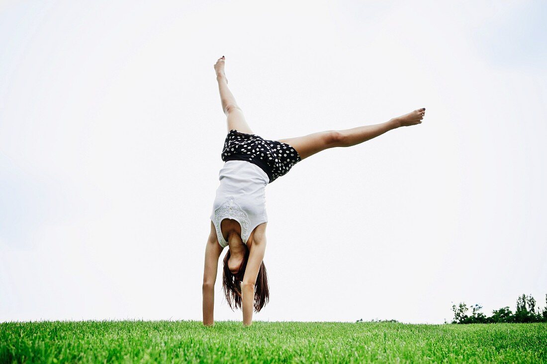 Teenager doing a handstand on a lawn
