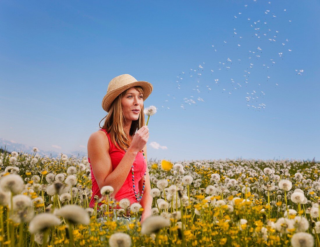 Woman puffing on a dandelion clock