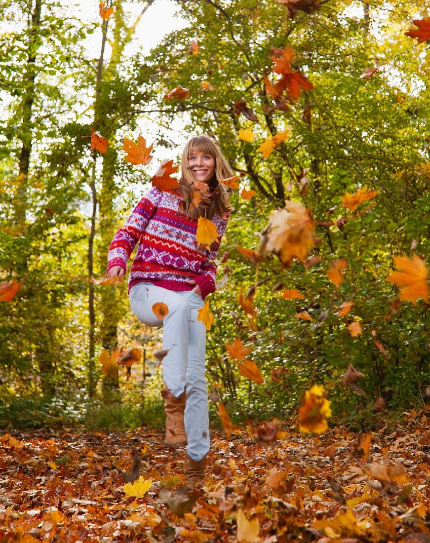 Woman jumping in autumn leaves