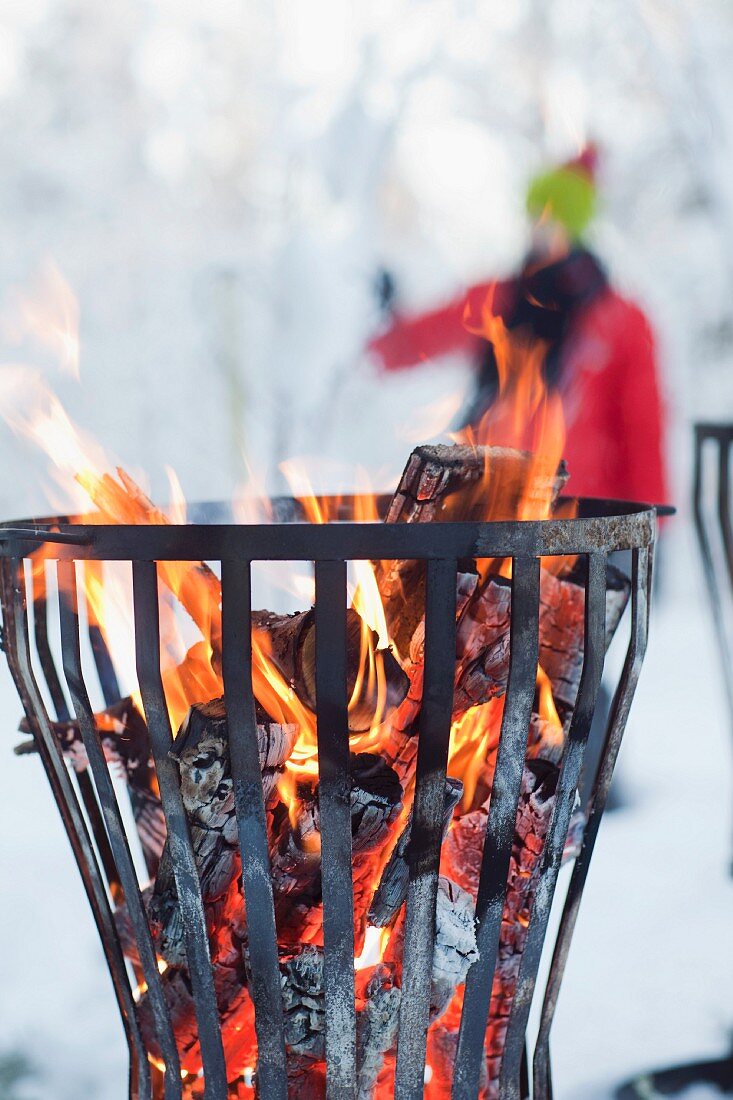 Log fire burning in metal basket in snow