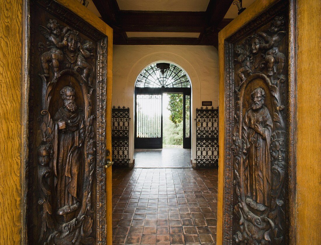Villa mit offenen Türen und holzgeschnitzten Menschenfiguren auf Paneelen und Blick in Vorraum