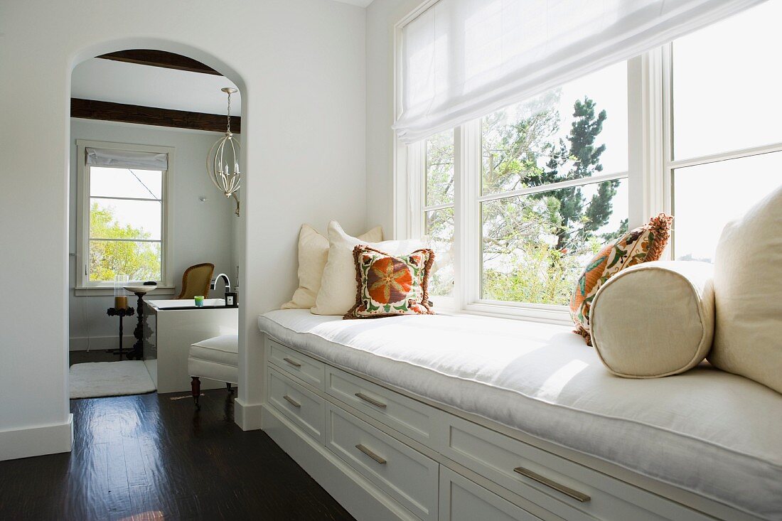 Bench along window in hallway of white contemporary home