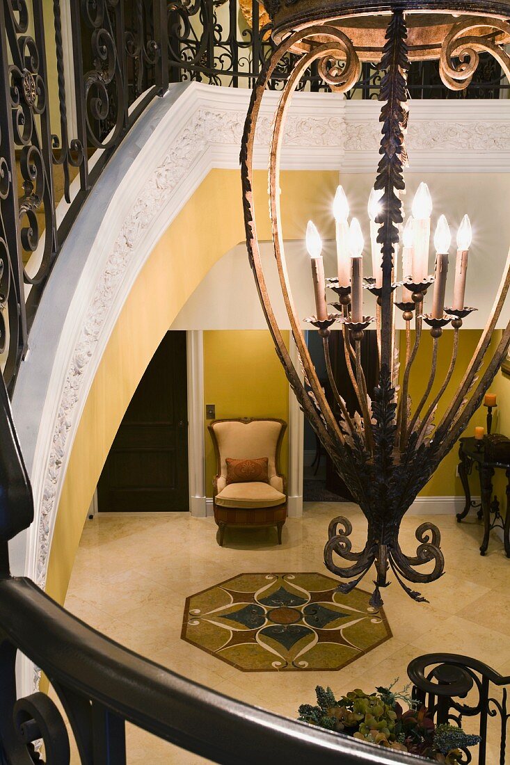 Antiker Kerzenleuchter und Blick von oben auf ein Fliesenornament in die Eingangshalle einer herrschaftlichen Villa