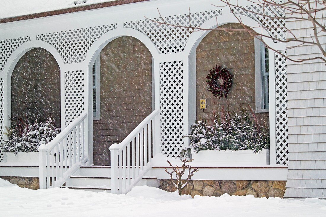 Front porch of shingle style home covered in snow