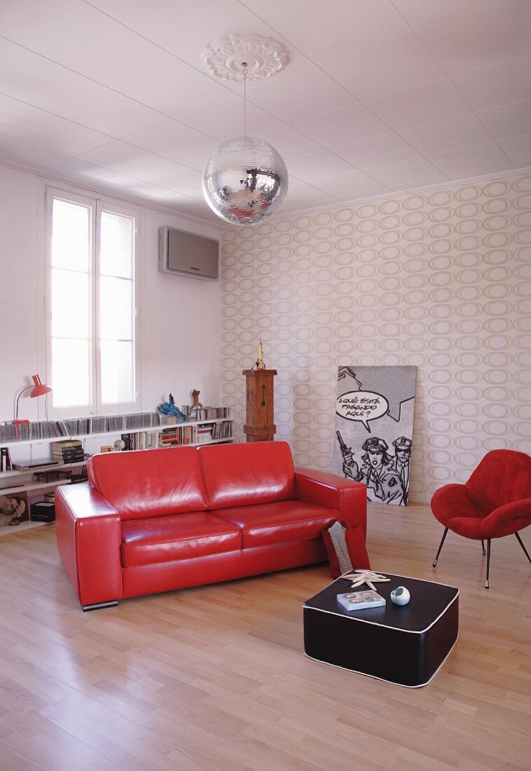 Rote Lack Couch und schwarzer Bodentisch auf Holzboden in minimalistischem Wohnzimmer mit Retro Flair