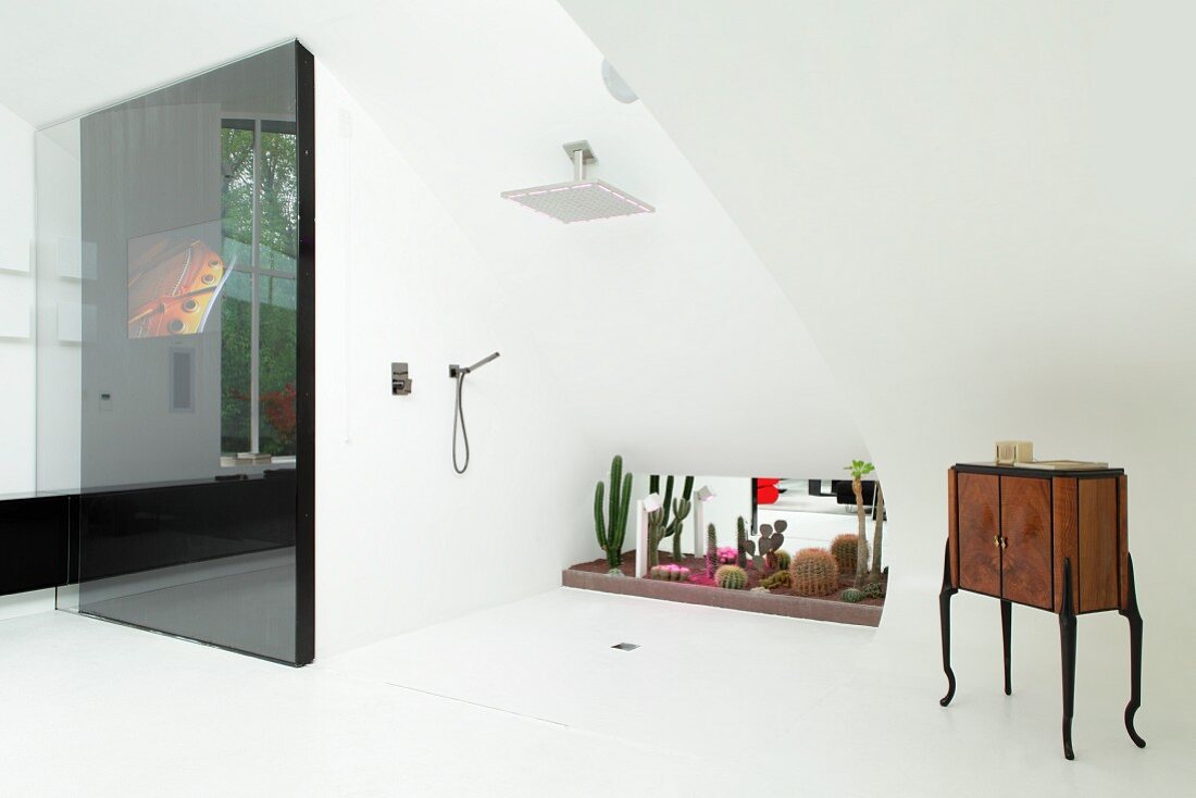 Exklusives Bad mit bodenebener Dusche vor Kakteensammlung am Fenster und antikes Schränkchen auf weißem Fliesenboden und mit schwarzer Schiebeelement