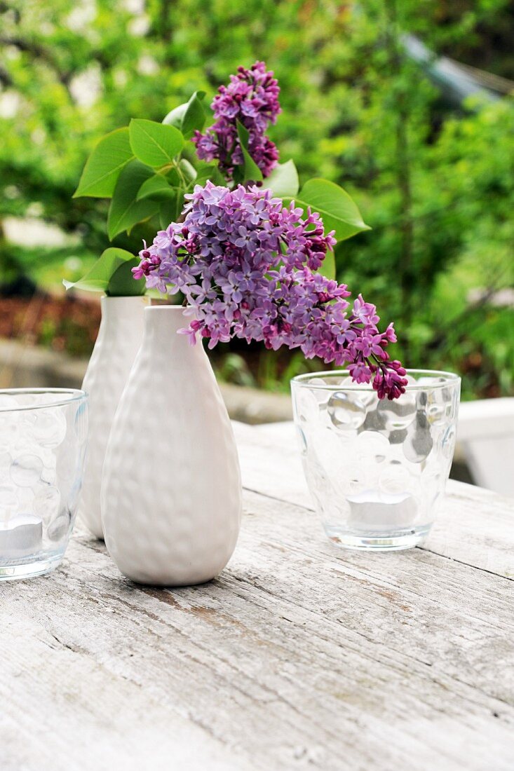 Violetter Flieder in Vase auf Gartentisch