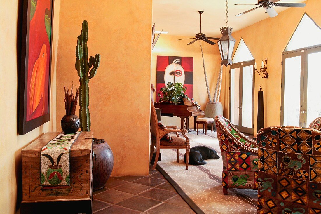 Rustikale Kommodel und Sessel mit folkloristischem Stoffbezug in offenem gelb getönten Wohnraum eines mexikanischen Landhauses