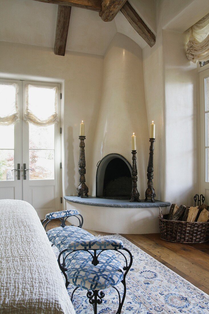 Kerzenständer um eingebauten Eckkamin und gepolsterte Sitzbank im Schlafzimmer eines Landhauses