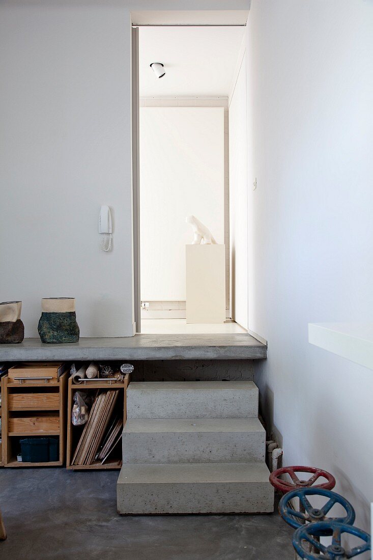 Concrete steps leading to raised platform above storage space