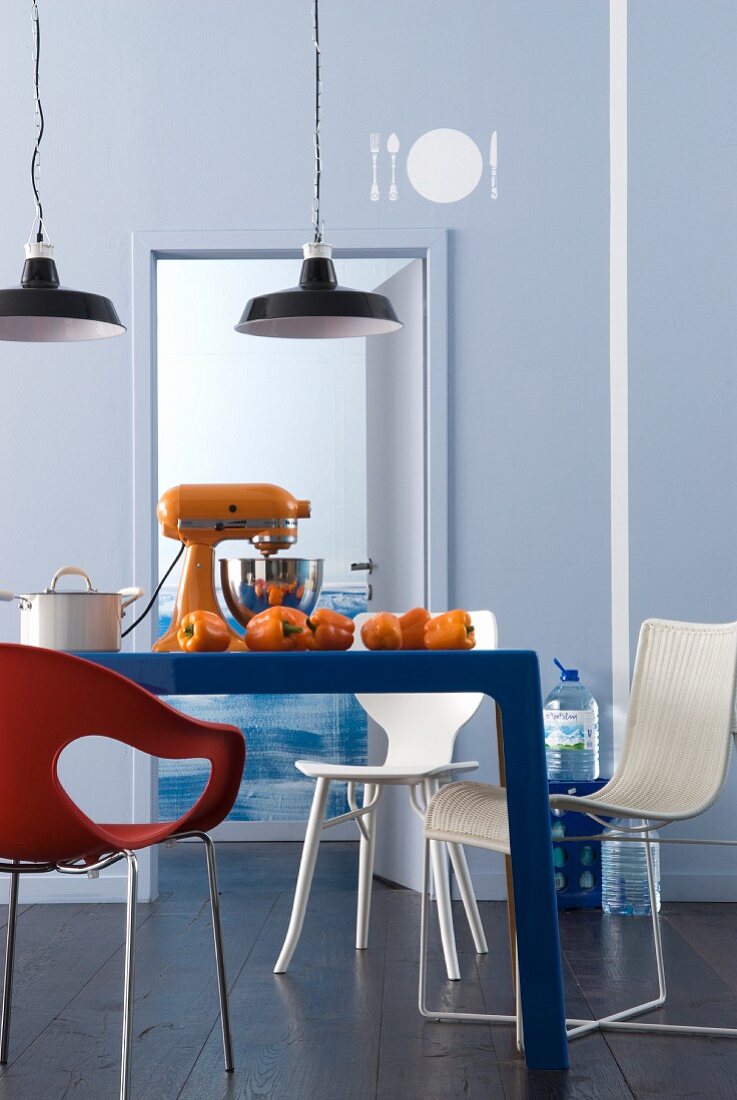weiße Muster auf grau-blauer Wand in einer Küche mit Küchengerät auf dem Tisch