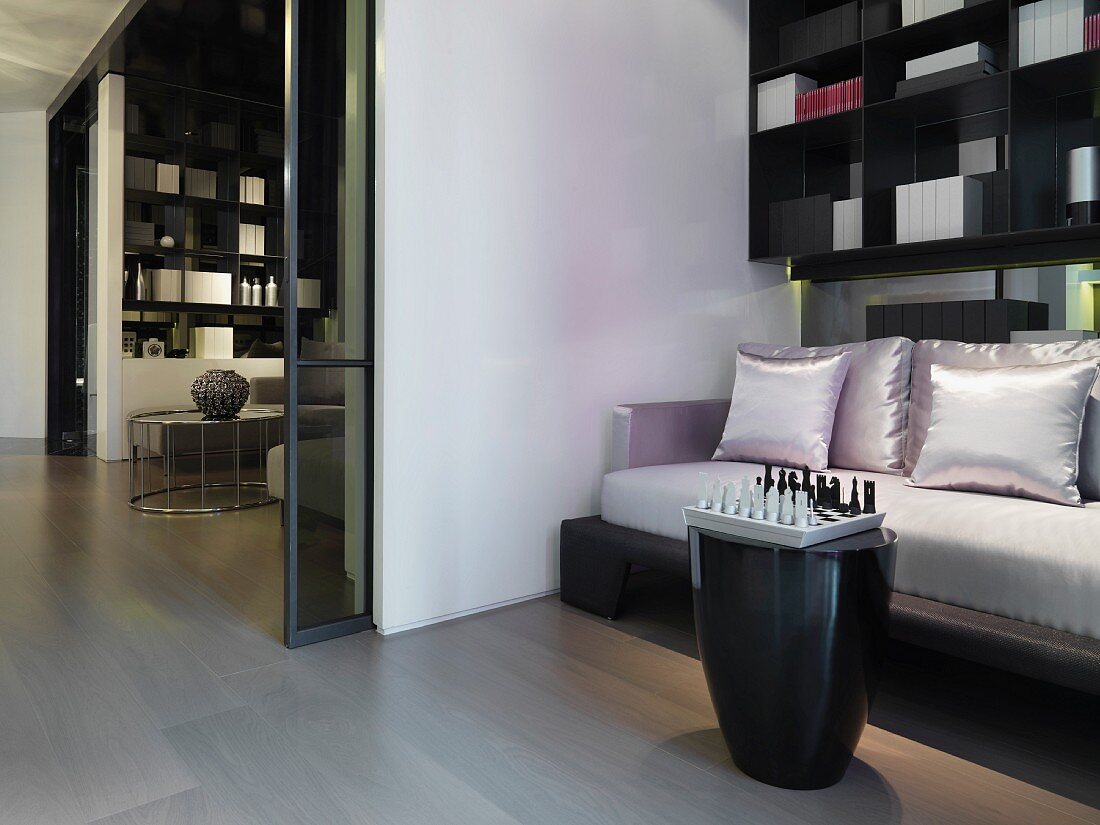 Sofa und Kissen mit glänzendem Stoffbezug vor Einbauregal und offene Glasschiebetür mit Blick in Wohnraum