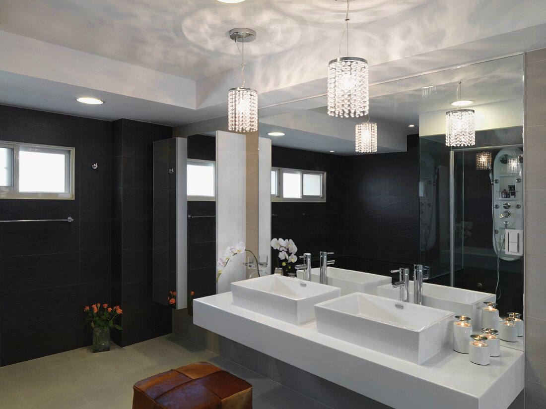 Designer Bad mit Waschtisch vor vollflächigem Wandspiegel und Hängelampen mit Glasperlenschmuck