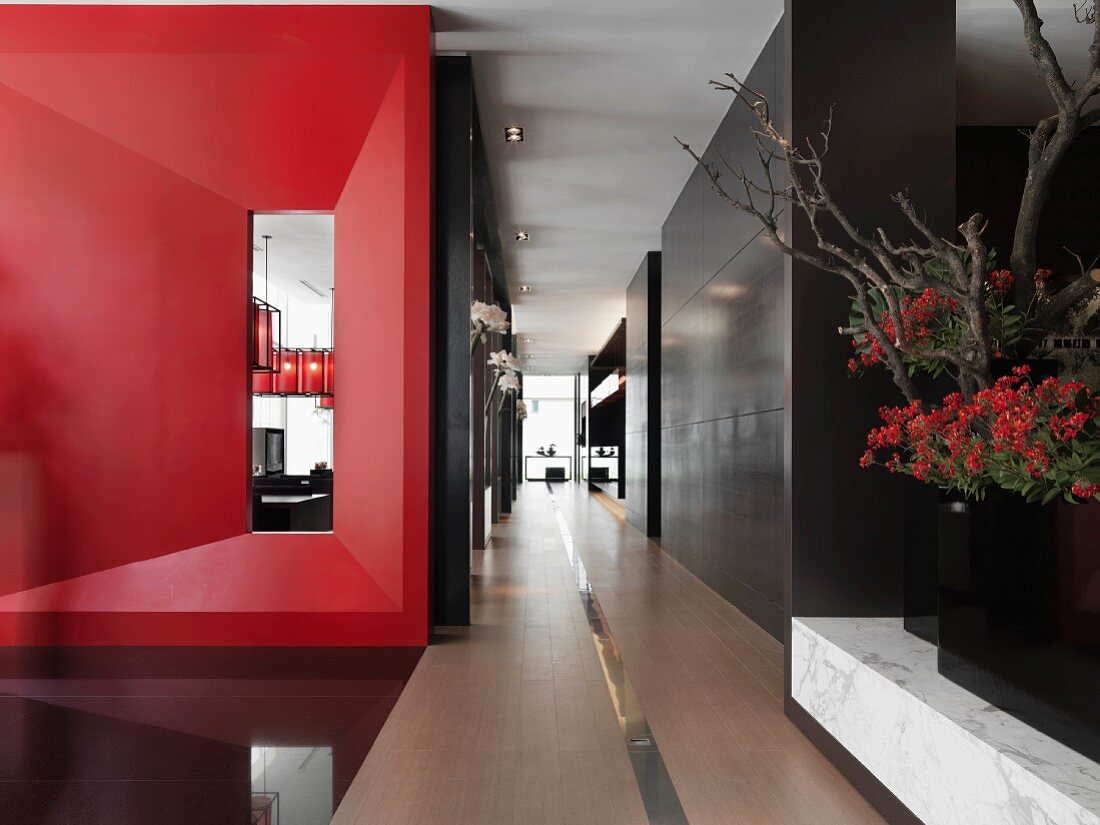 Offener Gangbereich mit roter, dreidimensionaler Wand und Schrankeinbauten in Designer Wohnung