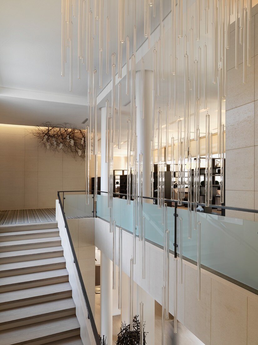 Grosszügige Treppenhalle mit Lichtobjekt aus hängenden Glasstäben an Decke