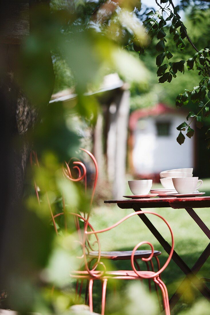 Filigraner Metallstuhl am Gartentisch mit Nachmittagskaffee