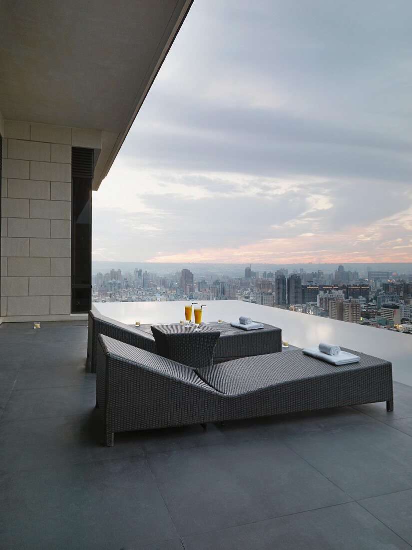 Modern outdoor loungers on roof terrace with view over cityscape