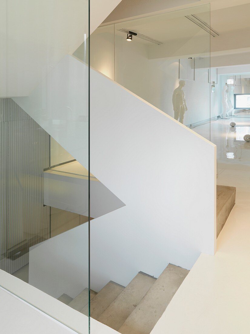 Stairwell with white, solid banister and glass partition in contemporary building
