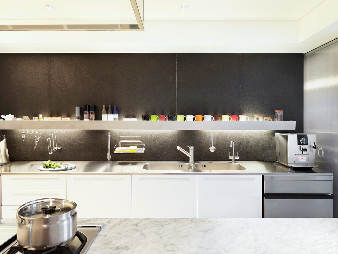 Designerküche mit weisser Küchenzeile und hinterleuchteter Ablage vor dunkelgrauer Wand