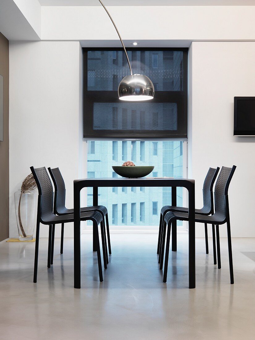 Black table with chairs in front of window in white dining room