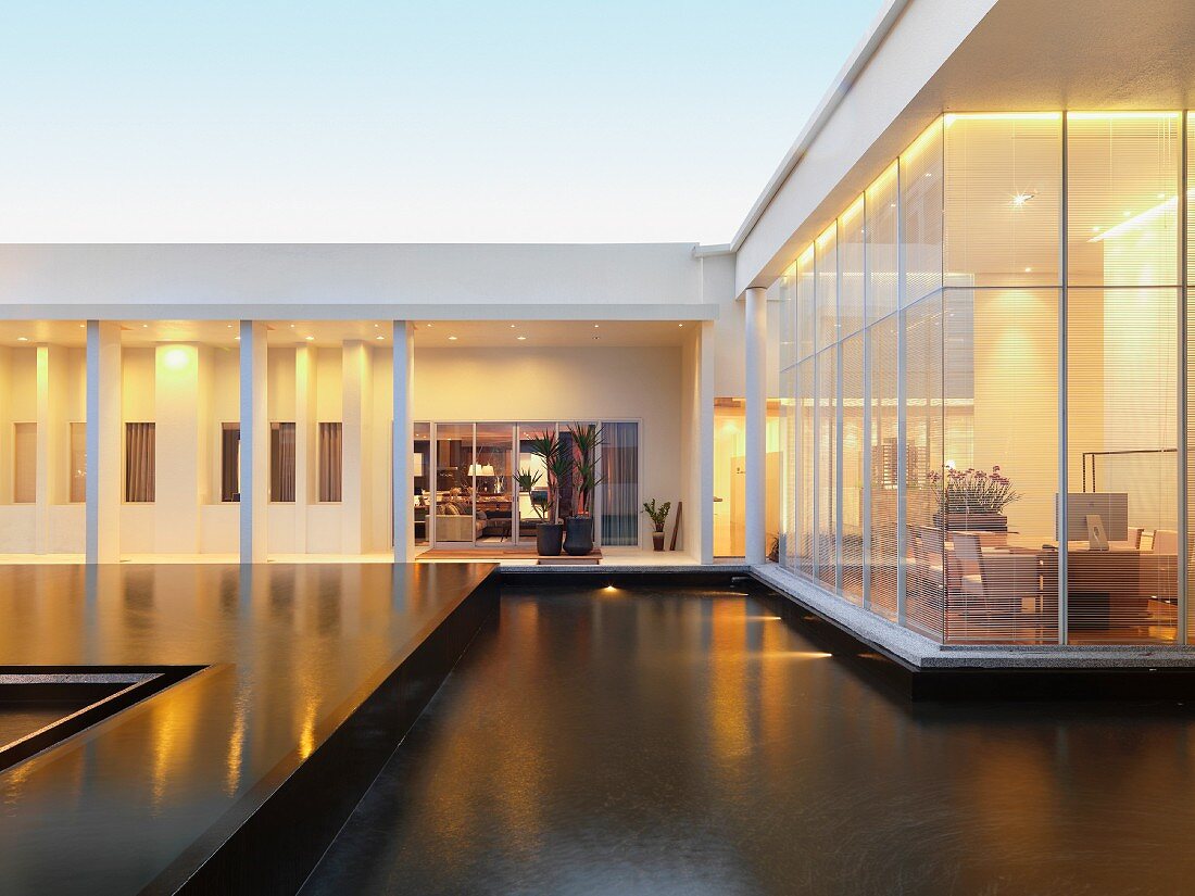Contemporary building with pool in courtyard and view into illuminated rooms