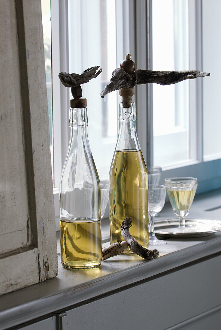 Oil bottles with decorative driftwood caps on windowsill